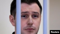 FILE - Former U.S. Marine Trevor Reed stands inside a defendants' cage during a court hearing in Moscow, Russia, March 11, 2020.