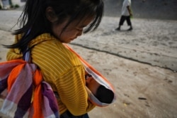 A Karen migrant living in Thailand holds her one-month-old baby in Mae Sam Laep town on the Thai side of the Salween river in Mae Hong Son province on April 2, 2021, across from where Myanmar refugees earlier attempted to cross the Thai border.