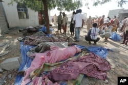 People stand near bodies of people who were killed at the al-Zaydiya security headquarters, that was destroyed by Saudi-led airstrikes Saturday, in the Red Sea port city of Hodeida, Yemen, Oct. 30, 2016.