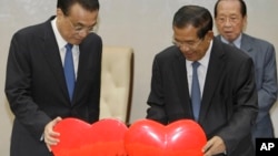 China's Premier Li Keqiang, left, pulls a symbol of China-Cambodia Heart Journey, together with his Cambodian counterpart Hun Sen, center, during a signing ceremony at Peace Palace in Phnom Penh, Cambodia, Thursday, Jan. 11, 2018.