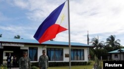 Filipino soldiers stand at attention near a Philippine flag at Thitu island in disputed South China Sea, April 21, 2017.
