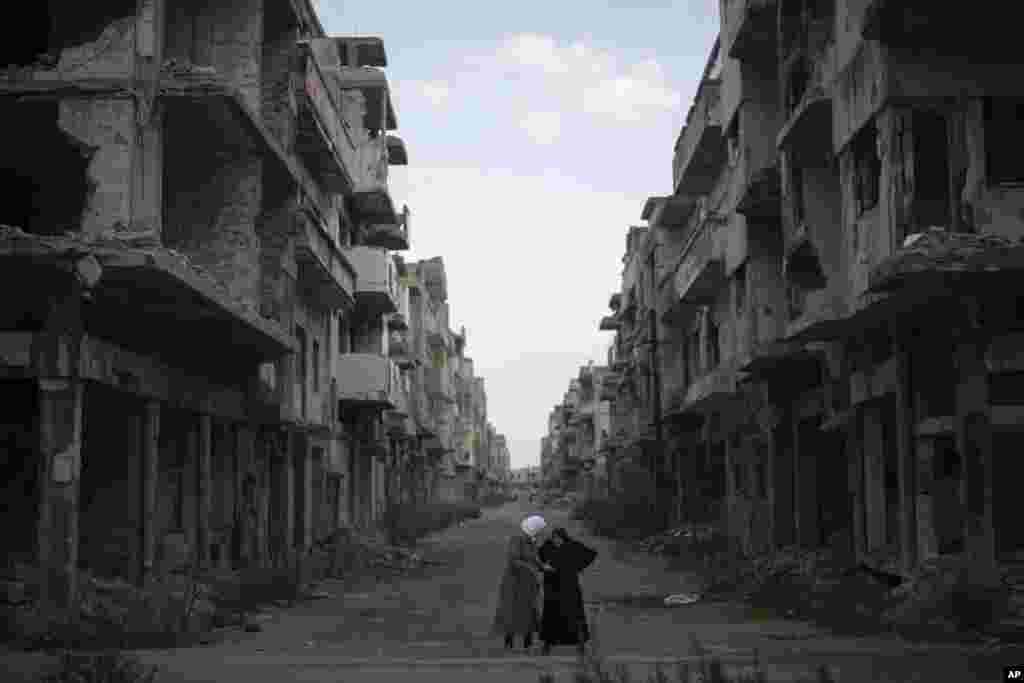 Women talk on a street surrounded by buildings that were destroyed during the civil war at the district of Khalidiya in Homs, Syria.