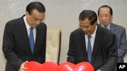 រូបឯកសារ៖ លោកLi Keqiang នាយក​រដ្ឋ​មន្ត្រី​ចិន (ឆ្វេង) ទាញ​រូប​បេះដូង​ដែល​តំណាង​ឲ្យ​ដំណើរ​នៃ​ក្តីស្រឡាញ់​ពី​បេះដូង​រវាង​កម្ពុជា និង​ចិន ជាមួយ​សមភាគី​របស់​លោក គឺ​នាយក​រដ្ឋមន្រ្តី​ខ្មែរ លោក ហ៊ុន សែន (កណ្តាល) ក្នុង​អំឡុង​ពិធី​ចុះ​ហត្ថលេខា​នៅ​វិមាន​សន្តិភាព​ក្នុង​រាជធានី​ភ្នំពេញ នៅថ្ងៃទី ១១ ខែមករា ឆ្នាំ២០១៨។​​ (រូបថត AP)