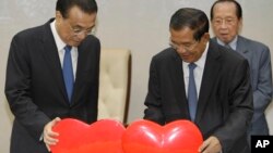 China's Premier Li Keqiang, left, pulls a symbol of China-Cambodia Heart Journey, together with his Cambodian counterpart Hun Sen, center, during a signing ceremony at Peace Palace in Phnom Penh, Cambodia, Thursday, Jan. 11, 2018. 