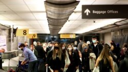 FILE PHOTO: Travelers wearing protective face masks to prevent the spread of the coronavirus disease reclaim their luggage at the airport in Denver, Colorado, Nov. 24, 2020.