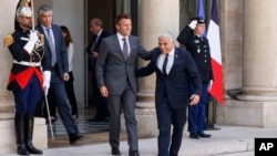 Presiden Prancis Emmanuel Macron (tengah, kiri) dan Perdana Menteri Israel Yair Lapid menuruni anak tangga untuk bertemu awak media setelah melangsungkan pertemuan di Istana Elysee di Paris, pada 5 Juli 2022. (Foto: AP/Thomas Padilla)