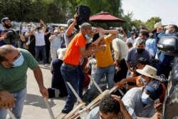 Supporters of Tunisia's biggest political party, the moderate Islamist Ennahda, take cover from stones thrown at them by supporters of President Kais Saied, outside the parliament building in Tunis, Tunisia, July 26, 2021.