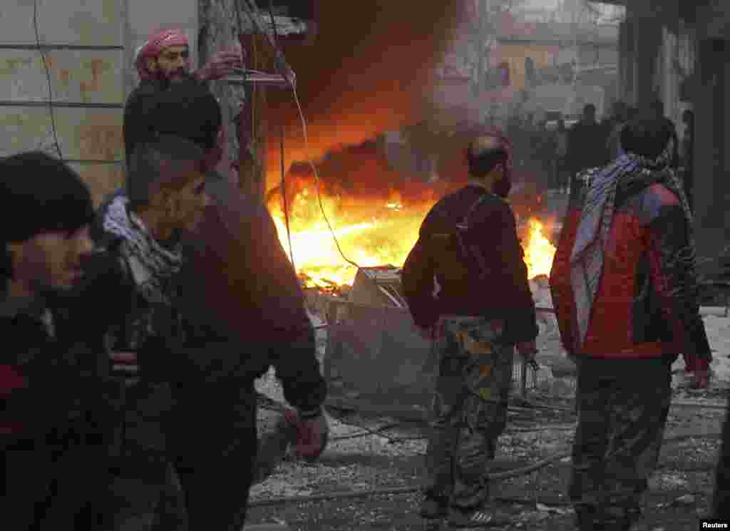 Free Syrian Army fighters stand near a fire after shelling by forces loyal to Syria's President Bashar al-Assad, al-Ansari, Aleppo, Syria, January 3, 2013.
