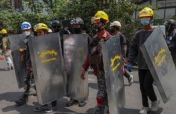Anti-coup protesters with makeshift shields walk to take positions in Mandalay, Myanmar, March 9, 2021.