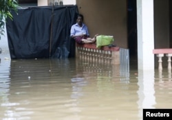 A man sits on a porch fence at his house caught in the flood in Nagoda village in Kalutara, Sri Lanka, May 29, 2017.