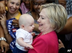 Democratic presidential candidate Hillary Clinton holds a baby as she greets people in the audience at a Pennsylvania Democratic Party voter registration event at West Philadelphia High School in Philadelphia, Aug. 16, 2016.