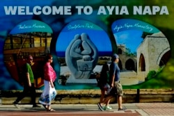 Tourists walk at southeast resort of Ayia Napa, in the eastern Mediterranean island of Cyprus, Saturday, May 22, 2021. (AP Photo/Petros Karadjias)