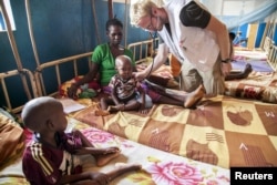 FILE -A doctor with the charity Medecins sans Frontieres (MSF) examines one of Marceline Wanou’s two sons as they recover from malnutrition in a hospital in Bambari, Central African Republic, Nov. 10, 2015.
