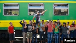 Adnan Shanan (tengah) seorang pengungsi dari Latakia di Suriah, ikut protes di depan kereta di stasiun kereta api Bicske, Hungaria, 4 September 2015. 