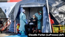 An elderly patient is attended in one of the emergency structures that were set up to ease procedures outside the hospital of Brescia, Northern Italy, Tuesday, March 10, 2020.