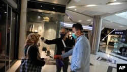 A woman has her temperature checked and her hands disinfected to help prevent the spread of the coronavirus as she enters the the Kourosh Shopping Center in Tehran, Iran, April 20, 2020.