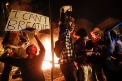 Protestors demonstrate outside of a burning Minneapolis 3rd Police Precinct, May 28, 2020, in Minneapolis.