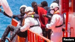 Arhiva - Migrantu, koji je dio grupe od 58 presretnutih na trošnom brodu na oko 100 milja od obale, pomažu spasioci nakon što je stigao u luku Arguineguin, Španija, 30. maja 2016.