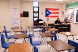 Ms. Martinez, seorang guru di Iroquois High School, berpindah-pindah antara kelasnya dan kelas anak-anaknya selama hari pembelajaran virtual. (Foto: Reuters)