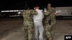 امریکی محکمہ دفاع کی طرف سے فراہم کردہ ویڈیو کا یہ اسکرین شاٹ 4 فروری 2025 کو پہلے طیارہ سے نیول سٹیشن گوانتانامو بے ہنچنے والے زیر حراست تارکین وطن کا ہے۔