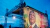 Men prepare stage for campaign rally beside poster for Malian presidential candidate Ibrahim Boubacar Keita, Bamako, Aug. 9, 2013.