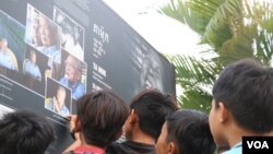 Primary school students in Anlong Veng look and read a banner about Khmer Rouge, placed inside Anlong Veng district hall compound, January 5, 2019. (Sun Narin/VOA Khmer) 