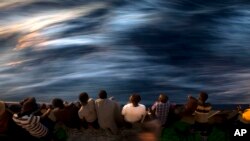 FILE - Migrants and refugees stand on the deck of the rescue vessel Golfo Azzurro after being rescued by Spanish NGO Proactiva Open Arms workers on the Mediterranean Sea, June 16, 2017. 