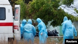 Petugas kota dan kerabat yang mengenakan pakaian pelindung mengeluarkan jenazah seorang wanita yang meninggal akibat virus corona di Chennai, India, 8 April 2020. (Foto: Reuters/P. Ravikuma)