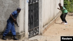 Policemen clash with protesters near a parliament building during a protest against Burundian President Pierre Nkurunziza's decision to run for a third term in Bujumbura, Burundi, May 13, 2015. 