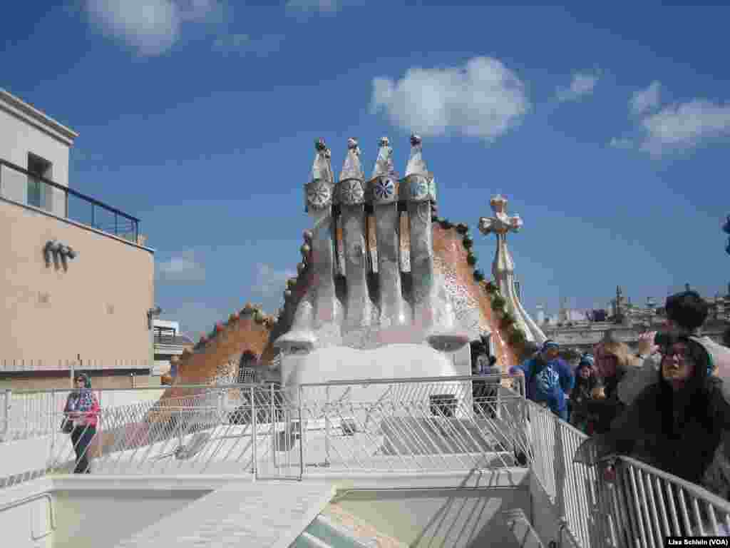 The mushroom-shaped chimney stack atop Casa Batllo. Behind the stack is the dragon and cross of St. George, in Barcelona.