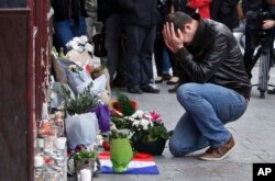 FILE - A man holds his head in his hands as he lays flowers in front of the Carillon cafe, in Paris, Nov. 14, 2015.