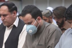 A man wearing a face mask as a precaution against COVID-19 offers Friday prayers with others in Peshawar, Pakistan, March 20, 2020.