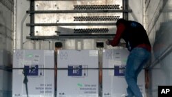 A health worker checks boxes of AstraZeneca COVID-19 vaccines inside a truck, that were delivered to Idlib through a border crossing with Turkey, in Bab Al-Hawa, northwestern Syria, April 21, 2021.