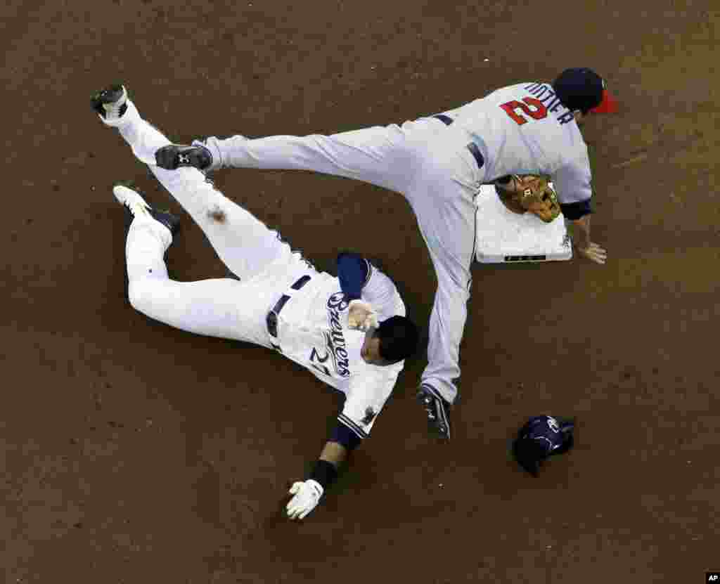 Minnesota Twins&#39; Brian Dozier (2) leaps over Milwaukee Brewers&#39; Carlos Gomez (27) at second base to turn a double play on a ball hit by Khris Davis during the fourth inning of a baseball game in Milwaukee, Wisconsin, USA, June 2, 2014.