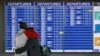 A man and woman embrace in front of a flight departures board at Dulles International Airport in Dulles, Va., Tuesday, March 17, 2020. (AP Photo/Patrick Semansky)