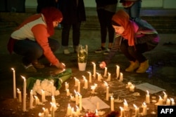 FILE - People stand by as a makeshift memorial is made after vigil at the University of North Carolina following the murders of three Muslim students, in Chapel Hill, N.C., Feb. 11, 2015.