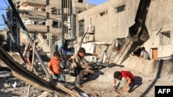 Watoto wakitafuta katika kifusi cha jengo lililoanguka ikiwa ni uharibifu unaotokana na mashambulizi yanayofanywa na jeshi la Israeli, katika eneo la shule ya Jaouni inayosimamiwa na shirika la misaada na ujenzi la UN (UNRWA) huko Nuseirat, katika Ukanda wa Gaza Julai 6, 2024.