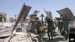 Egyptian Army soldiers clear away scrap metal used by protesters during clashes outside the Ministry of Defense in Cairo, Egypt, May 5, 2012.