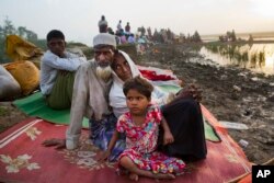 Rohingya man Nur Ahmad, 70, his wife Lalu Bibi and their grand daughter Ashuka Bibi, 5, who crossed over to Bangladesh the previous day, wait for permission to go to the refugee camps after spending the night in the rice fields near Palong Khali, Banglade