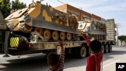 រូបឯកសារ៖ ក្មេងៗគ្រវីដៃទៅកាន់កងកម្លាំងតួកគី ដែលកំពុងដឹករថពាសដែកទៅកាន់តំបន់ព្រំដែន កាលពីថ្ងៃទី១៥ ខែតុលា ឆ្នាំ២០១៩។ 