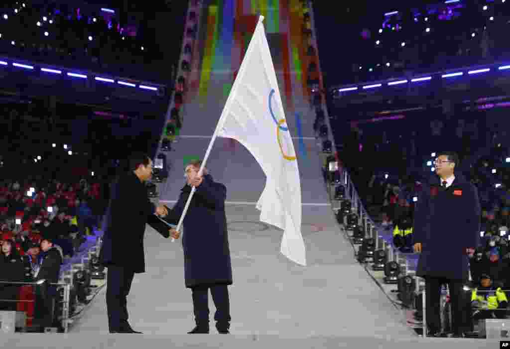 International Olympic Committee President Thomas Bach, center, receives the Olympic flag from Sim Jae-guk, left, the mayor of Pyeongchang, during the closing ceremony of the 2018 Winter Olympics, Feb. 25, 2018.