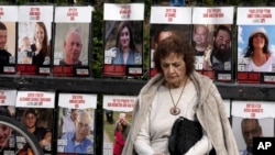 A woman pauses near posters of hostages held by Hamas in the Gaza Strip, in Tel Aviv, Israel, as Israel's security Cabinet convened, Jan. 17, 2025.
