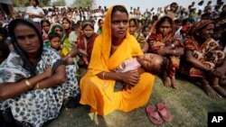 In this photo taken Monday, Feb. 10, 2014, migrant villagers gather to attend the awareness and service camp under National Rural Health Mission at a very remote Baralakhaiti village on the sandbars of River Brahmaputra, about 70 kilometers (43 miles) north of Gauhati, India.