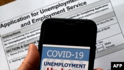 FILE - A COVID-19 Unemployment Assistance Updates logo is displayed on a smartphone against the backdrop of an application for unemployment benefits, in Arlington, Virginia.