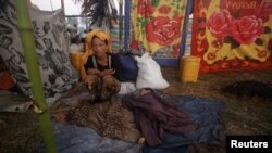 FILE - A woman displaced byviolence in Pauktaw sits by her sleeping child at Owntaw refugee camp for Muslims outside Sittwe, Rakhaine state, Burma.