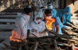 Para kerabat dari seorang pasien COVID-19 yang meninggal menyalakan api di tempat pembakaran jenazah di sebuah krematorium di Jammu, India, Senin, 26 April 2021. (Foto: Channi Anand/AP)