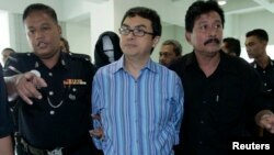 FILE - Abdul Razak Abdullah Baginda, center, is escorted by policemen as he leaves the courtroom in Shah Alam outside Kuala Lumpur, Sept. 3, 2007. Razak, 46, a close aide of Najib Razak, has been accused of involvement in the murder of 28-year-old Mongolian model.