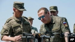 Russian Security Council Deputy Chairman and the head of the United Russia party Dmitry Medvedev, right, listens to an officer as he visits the Pogonovo military training ground in Voronezh region of Russia, July 17, 2024.