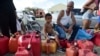 Ricardo Gonzalez sits on a gas container with his uncle Miguel Colon as hundreds of people wait in line since early morning hours to buy gasoline three days after the impact of Hurricane Maria in Carolina, Puerto Rico, Sept. 23, 2017.