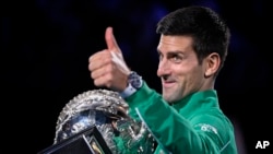 Petenis Serbia Novak Djokovic memberi isyarat ketika ia memegang setelah mengalahkan Austria Dominic Thiem di final kejuaraan tenis Australia Terbuka di Melbourne, Australia, Senin, 3 Februari 2020. (Foto: AP/Andy Brownbill)